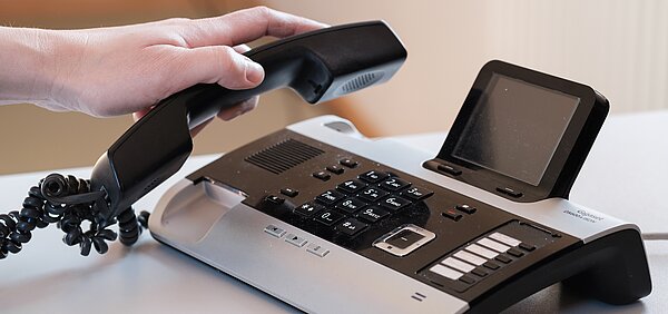 Hand, die einen Telefonhörer abnimmt